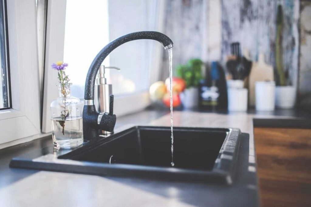 Water running from a black kitchen faucet into a matching black sink
