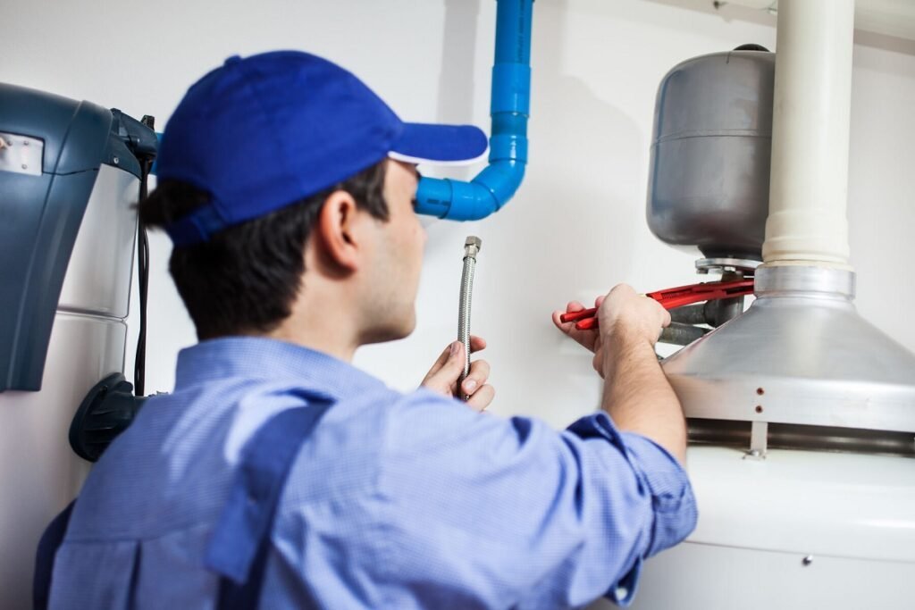 Plumber using a red wrench to connect a supply line to a water heater
