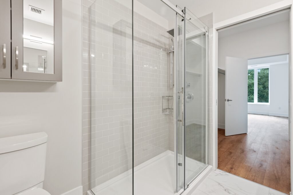 Glass-enclosed shower with white subway tile in a bright modern bathroom