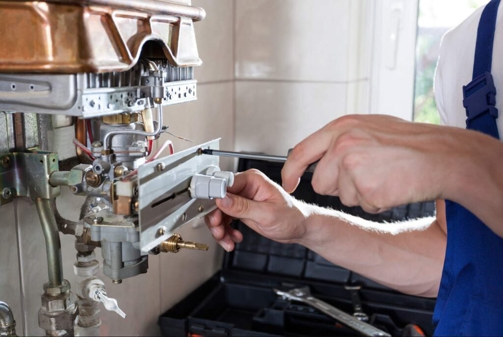 Hands using a screwdriver on the open burner assembly of a gas water heater