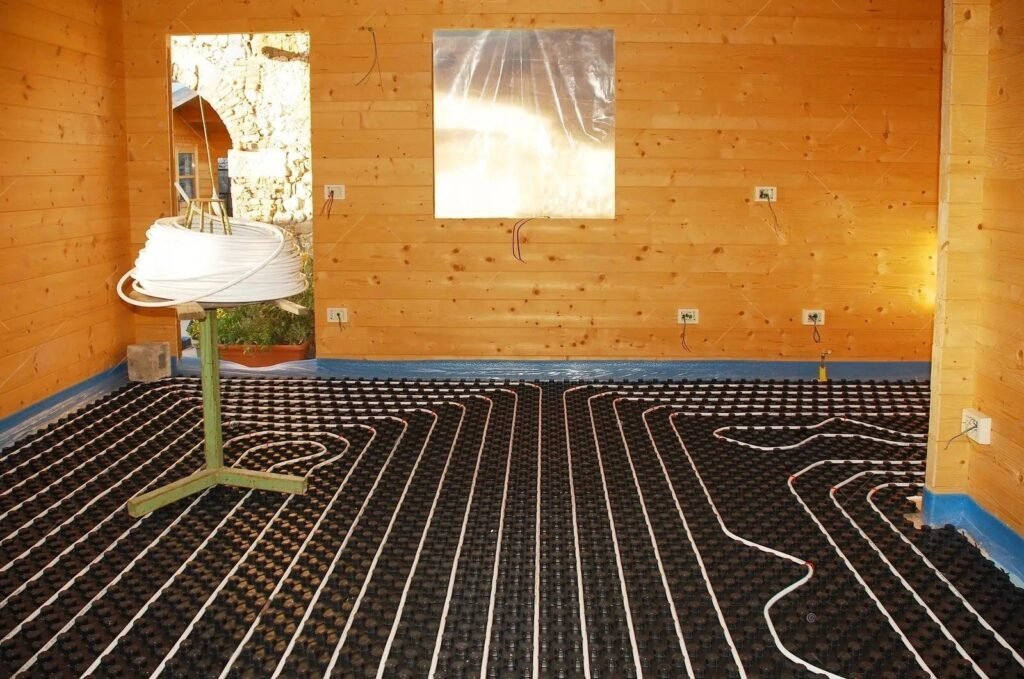 Radiant floor heating tubing laid across insulation panels in a wood-panelled room