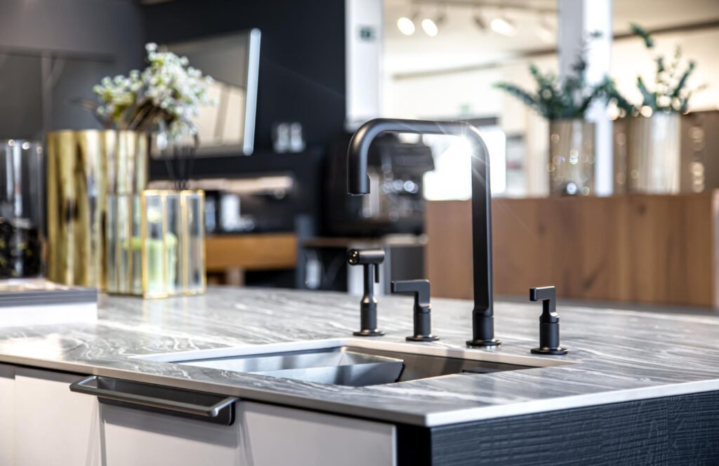 Matte black faucet above a stainless undermount sink in a marble countertop