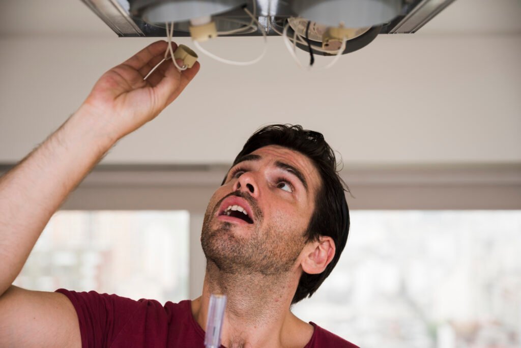 Technician looking up while connecting wiring in a ceiling light fixture