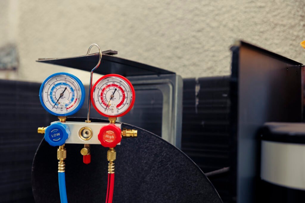 Refrigerant manifold gauge set with red and blue hoses on outdoor equipment